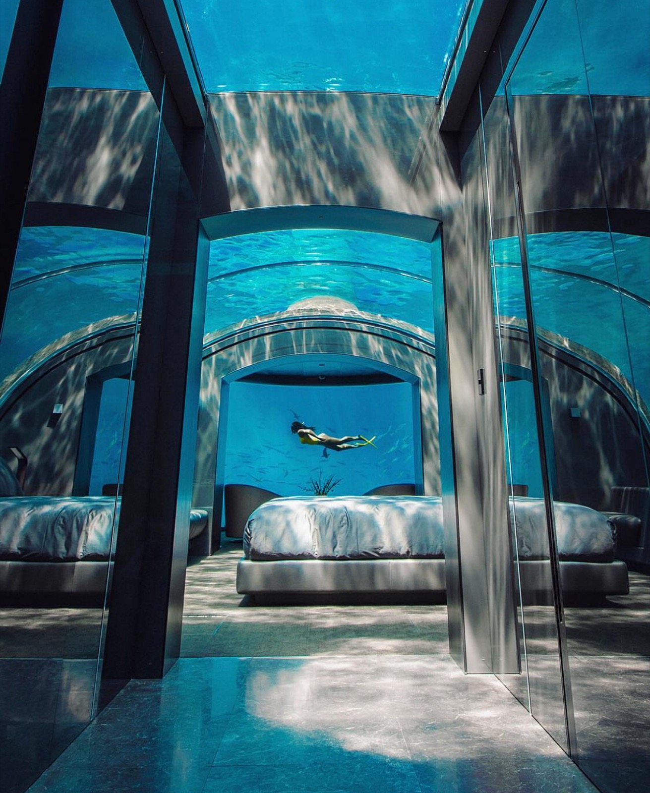 Underwater suite with a free diver swimming past the curved glass